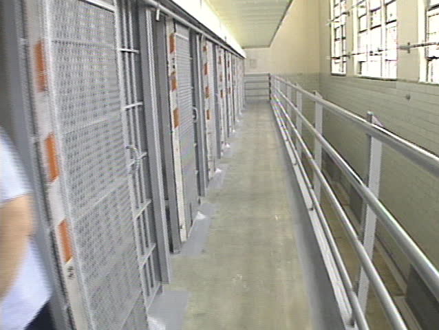 Walk down a row of cells in a prison. 