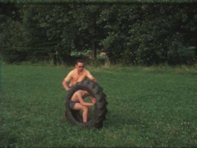 Vintage 8mm film: Boy in tire rolled by father, 1970s