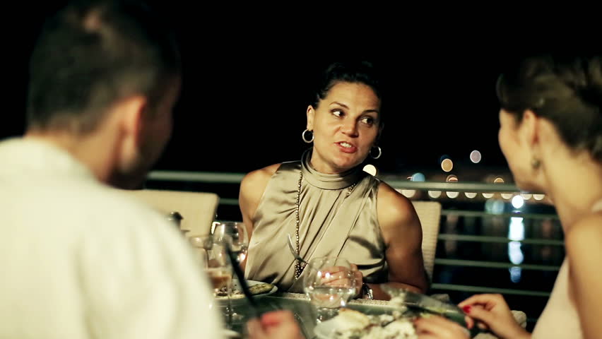 Group of friends celebrating dinner on the terrace at night, steadycam shot
