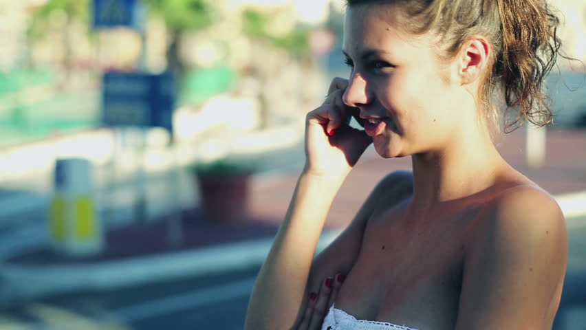 Young woman talking on cellphone on the street, steadycam shot
