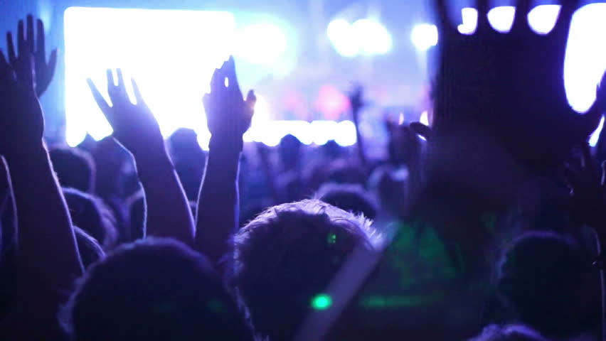 Shot of some cheering fans at a concert, slow motion, some visible noise due high ISO, soft focus