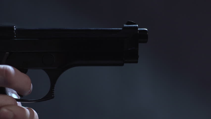 Close profile of man holding a 9 mm handgun, then takes a shot