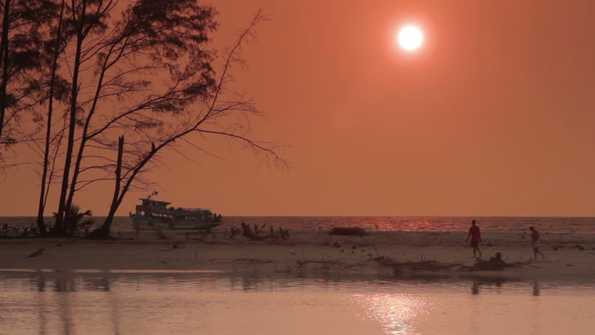 Sunset over the sea, sandbar and young couple exploring  Koh Kood Island, Thailand