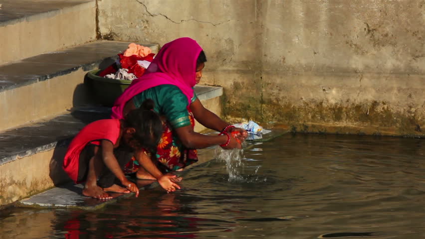 UDAIPUR, INDIA - NOVEMBER 24, 2012: Indian woman washing clothes in the lake in Udaipur, India, 24 nov 2012