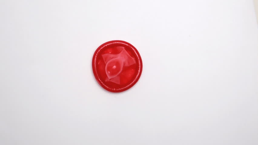 Red condom on revolving white surface
