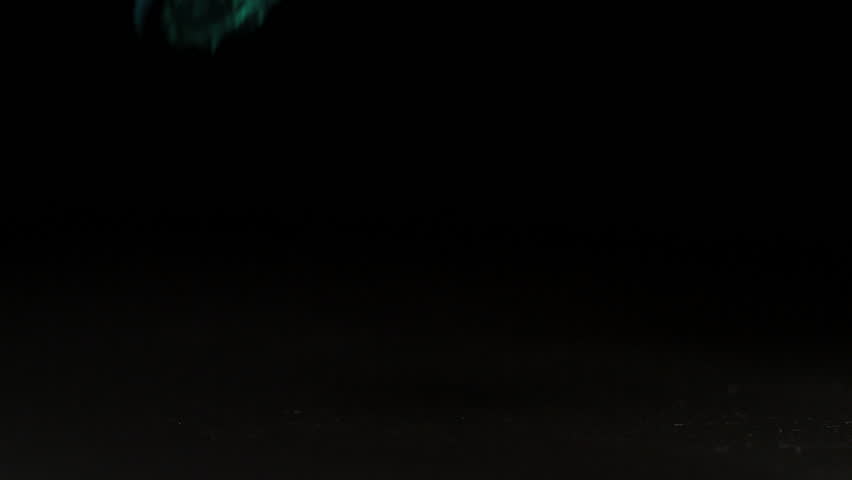 Couloured condoms falling over on black background in slow motion