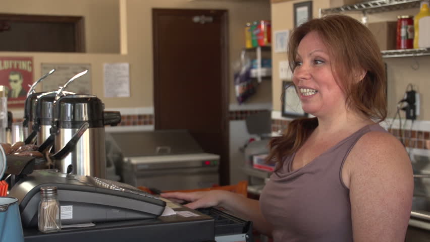 Woman at the register at her cafe with a customer