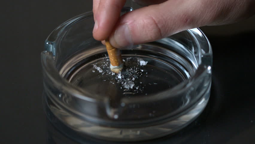 Hand putting out a cigarette in empty ashtray in slow motion