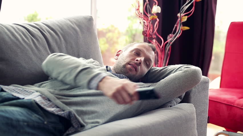 Bored man on sofa watching tv at home
