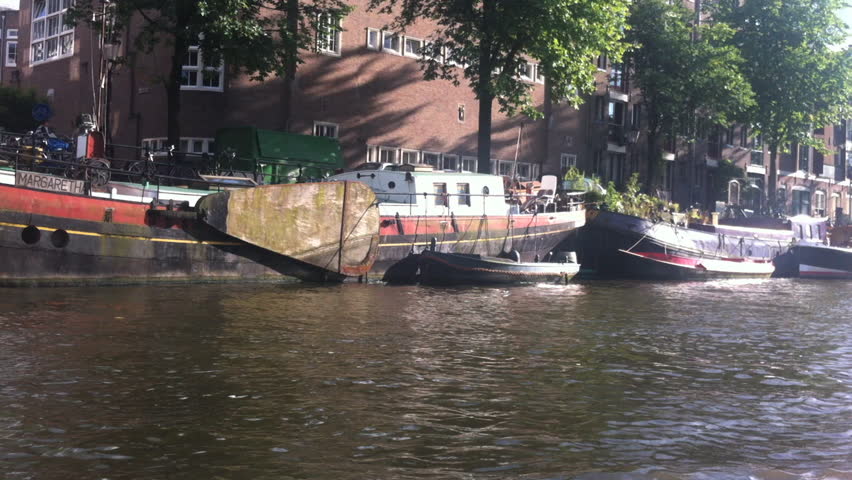 AMSTERDAM - SEPTEMBER 2012: POV from boat as it travels down canals, capturing bicycles, cars,bridges, and houseboats. The canals were placed on the UNESCO World Heritage List in 2010