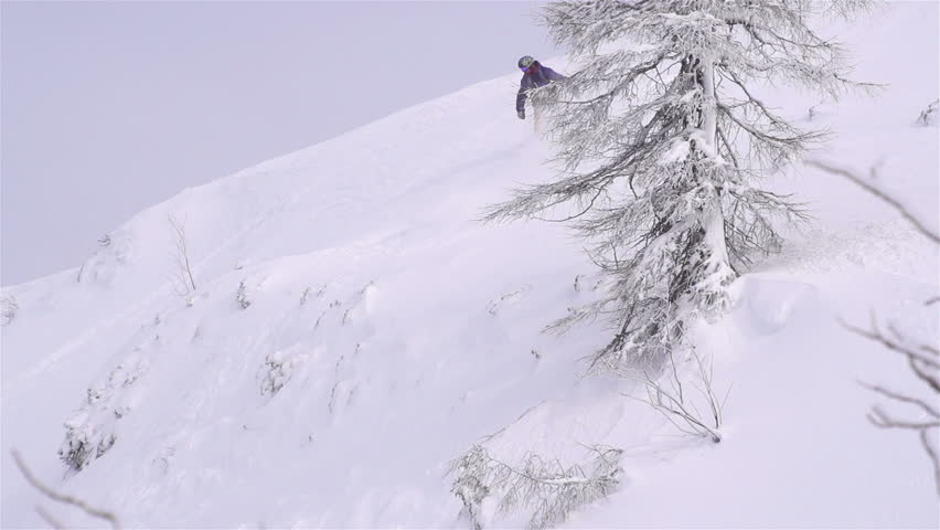 SLOW MOTION: snowboarder jumping over a cliff