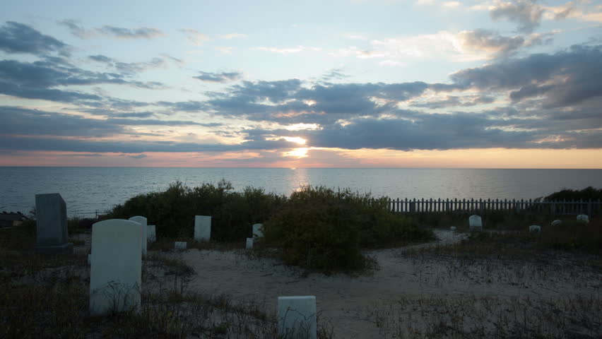 Sunset time-lapse at Graveyard near water with tombstones