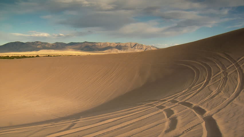 two ATV riders Circle large sand dune