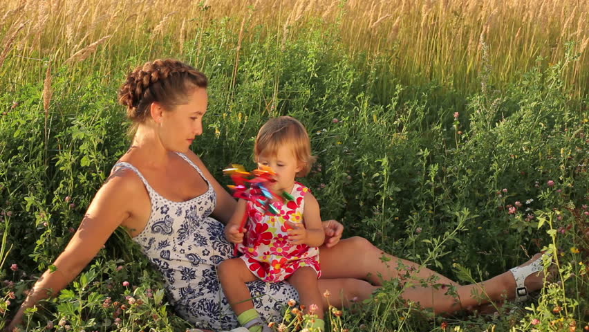Happy mother with cute baby on the meadow