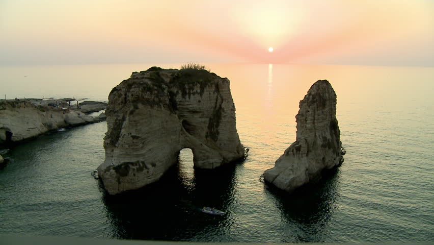 Medium shot High Angle of Al-Raouche rocks and small boat at sunset