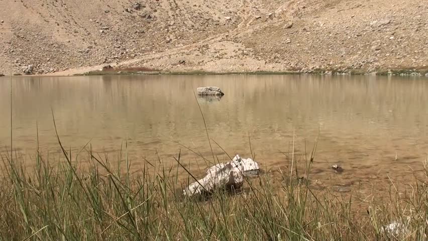 Water of crater lake, stones in it, reflection of surface