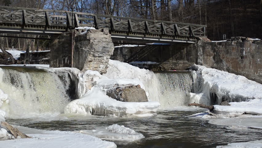 river waterfall retro bridge covered with frozen ice snow and icicles in winter.