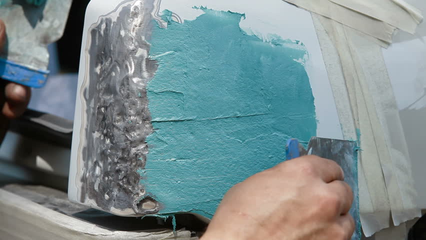 Smearing putty on damaged surface, close-up
