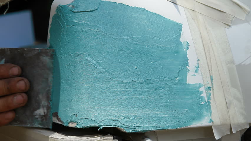 Close-up. Putty is being smeared on damaged car surface layer after layer.