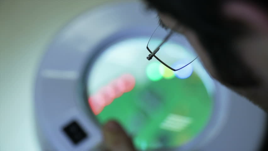 Young engineer analyzing  an electronic circuit board with a magnifying glass