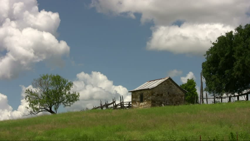 Video of an old pioneer rock shed or house on a hill. Time lapse with moving clouds.  Green fields  and wood fence and oak tree. Scenic   country.  Don Despain of Rekindle Photo