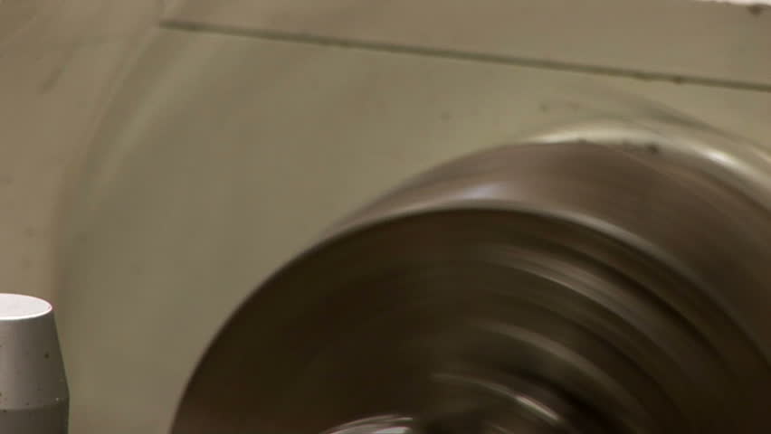 A stainless steel pipe spinning on a metal lathe.