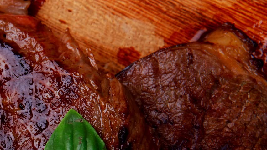 barbecued beef fillet on wooden plate with cutlery over table