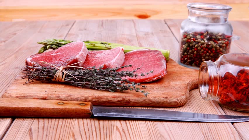 prime fillet meat : dry raw beef on cutting board with asparagus thyme bundle color peppercorn mix and red paprika powder mixed with dry spices over wooden table ready to cooking