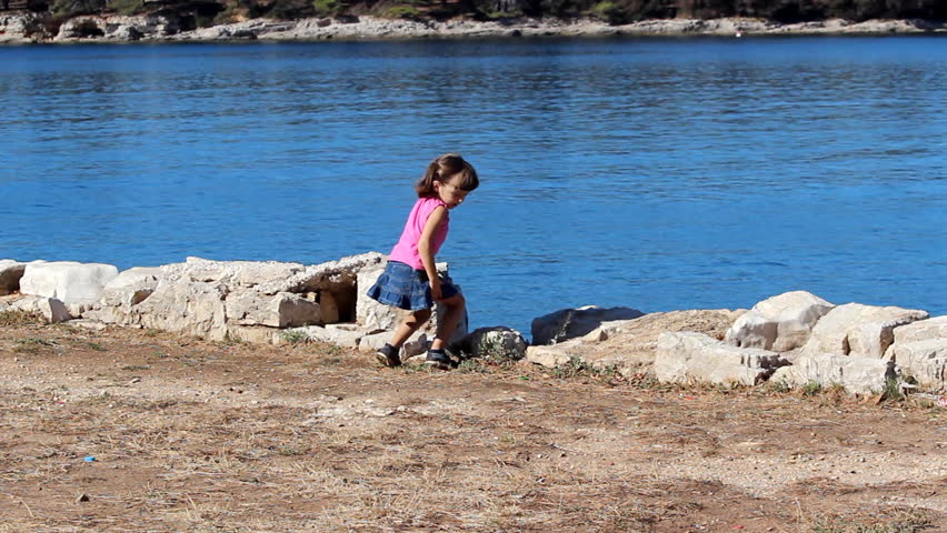 Kid and pebbles -  Small girl throwing pebbles at the sea.              
