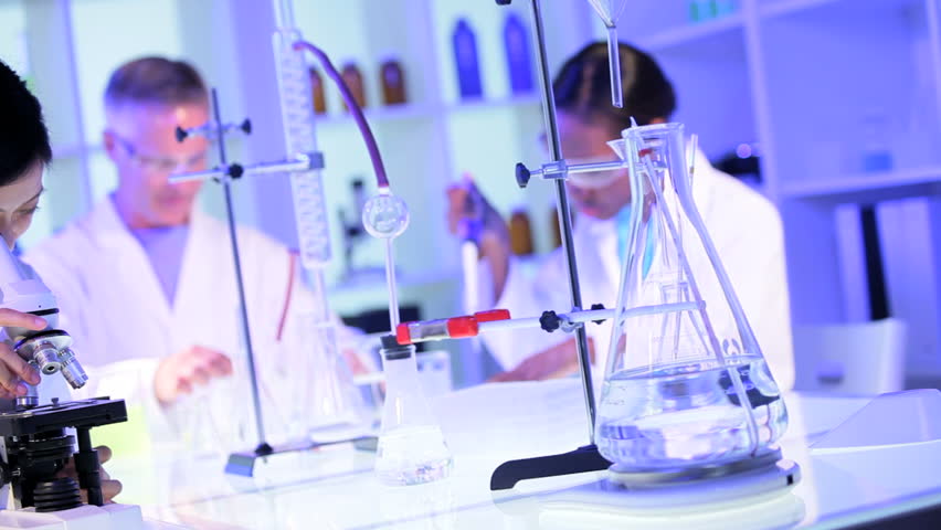 Medical students working with a microscope and test tubes in laboratory conditions