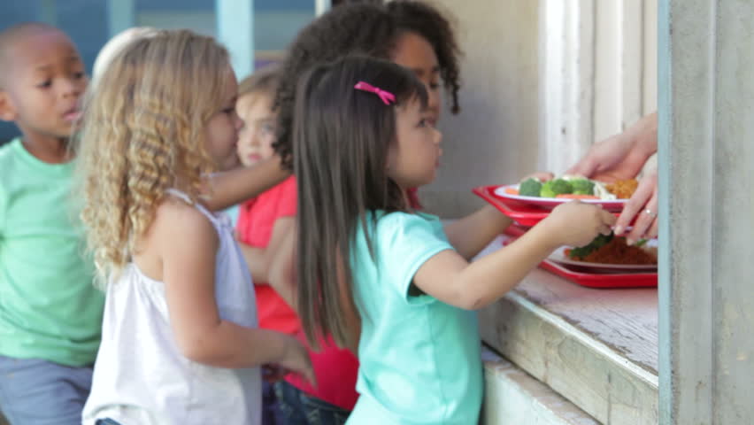 Cafeteria worker gives preschool students healthy lunches in school. Shot on Canon 5d Mk2 with a frame rate of 30fps