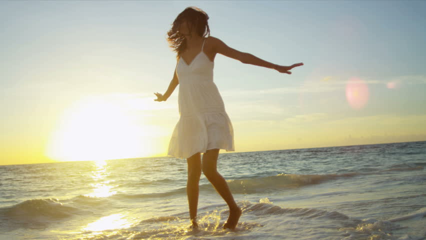 Pretty girl in sundress reveling being alone by ocean at sunrise on beach vacation shot on RED EPIC