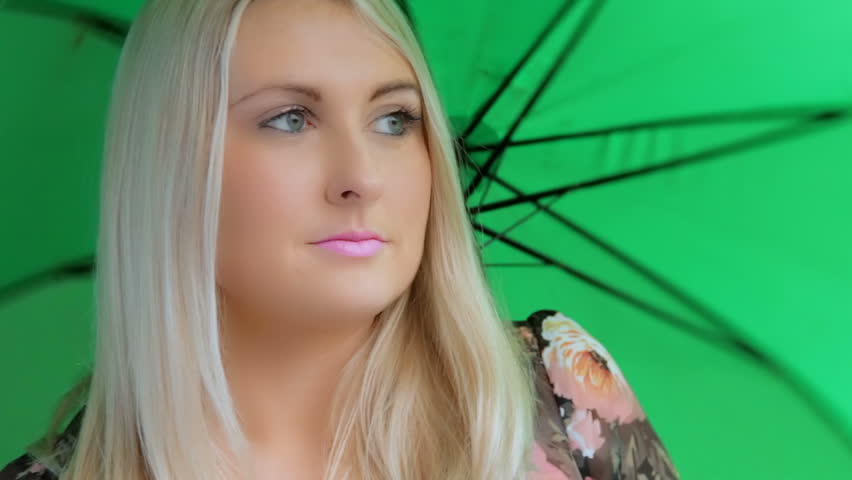 Girl with umbrella - A pretty girl twirls a bright green umbrella before turning away