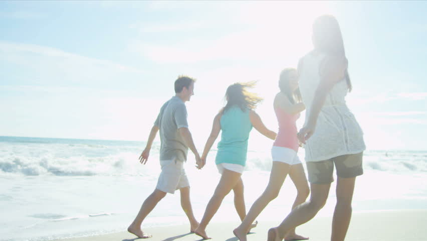 Healthy young family enjoying time together walking outdoors on the beach sun lens flare shot on RED EPIC