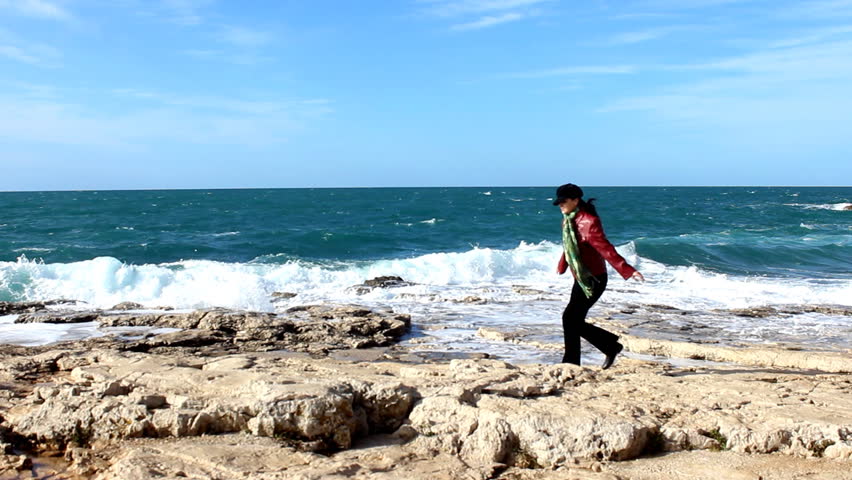 Balancing on rocks - Woman hopping on the coast. 