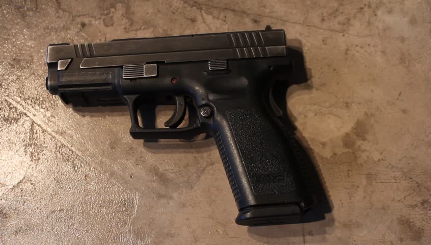 A handgun is slid across the table or counter, into the cameras view.
