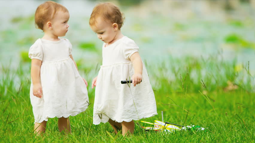 Caucasian girl twins toddling together in garden