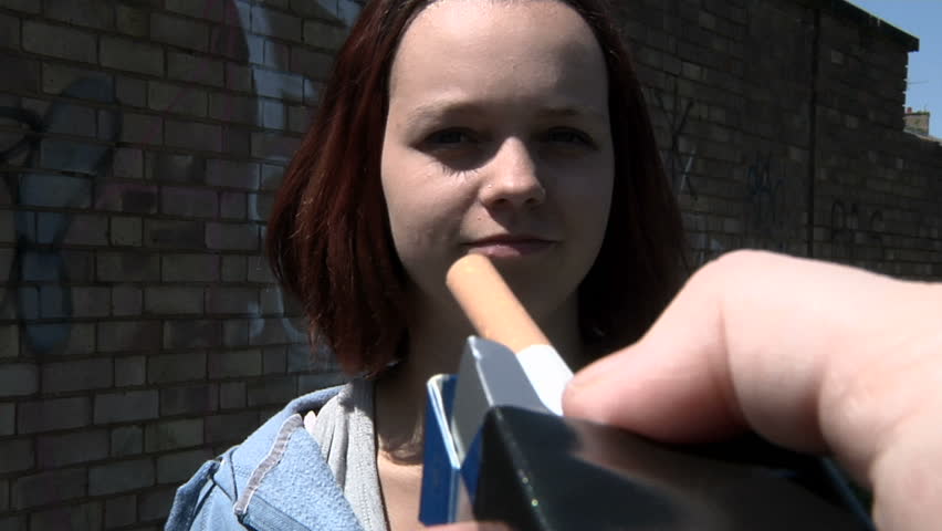 A teenage girl refuses a cigarette that is offered to her - resisting peer pressure
