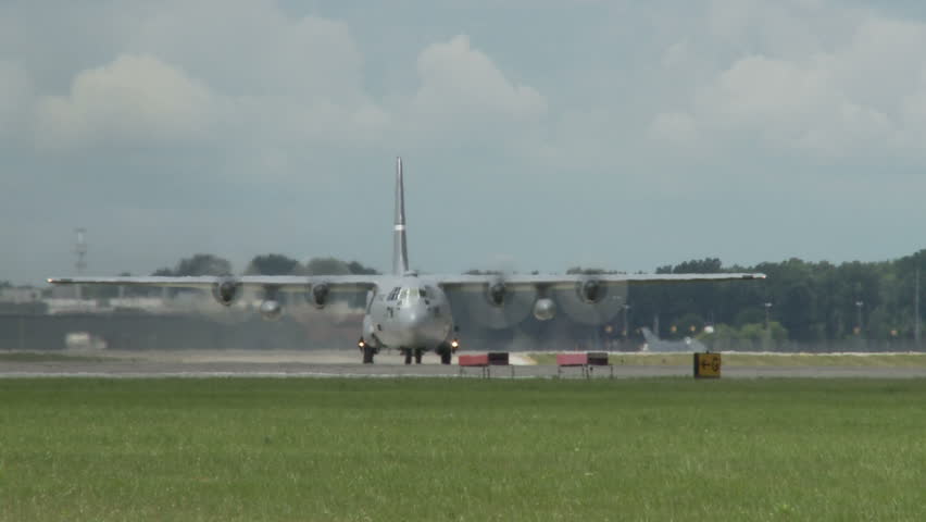 Lockheed Hercules military transport aircraft taxiing on airfield.  Head on view.