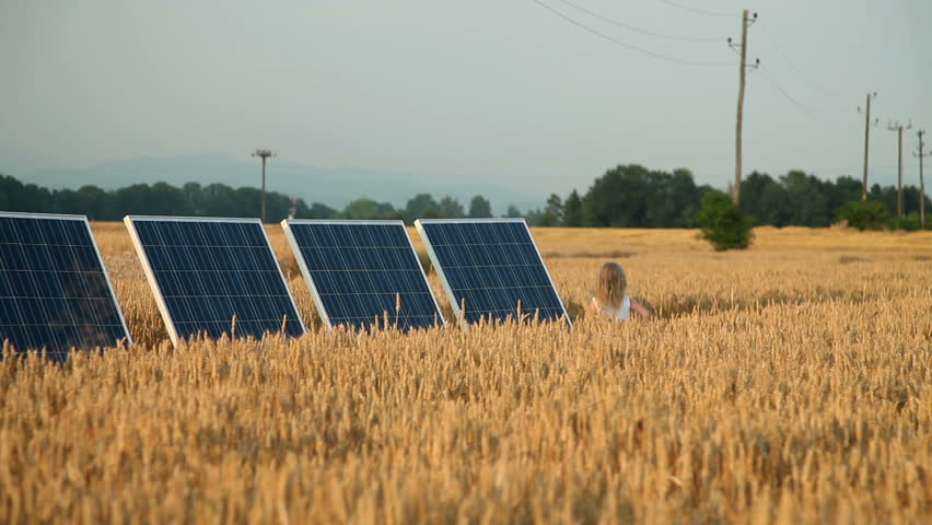 Little girl running on a golden field with solar power station