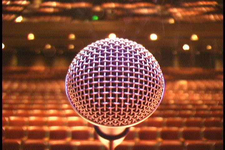 Closeup of a Microphone on Stage, then a slow upwards pan to the spotlights