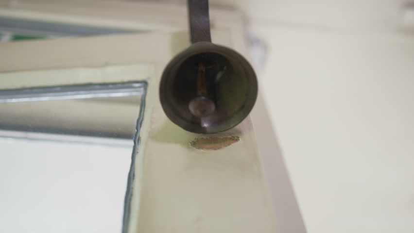 Quaint old fashioned bell ringing on a shop door to announce the arrival of a customer.