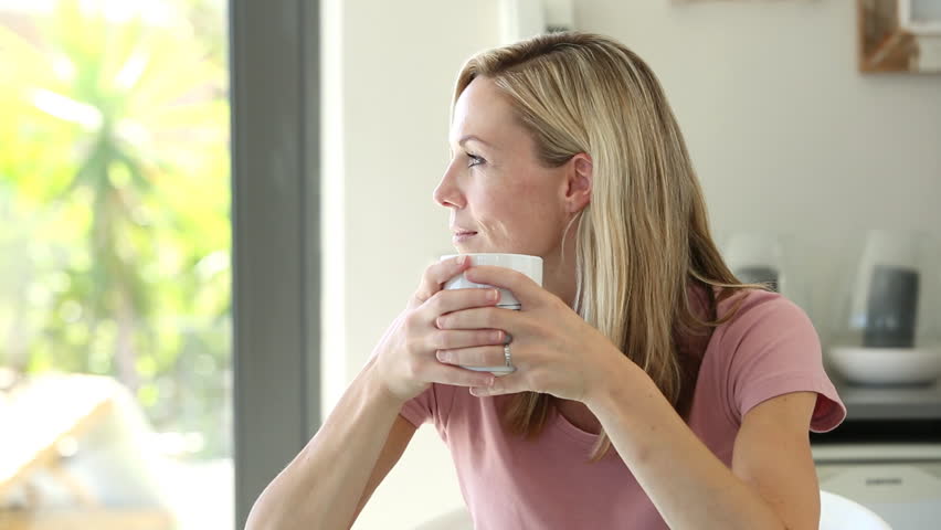 Blonde woman enjoying her drink while looking outdoors