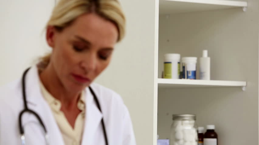 Doctor writing a prescription in her office