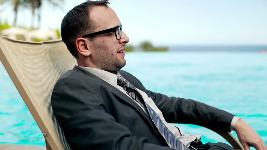 Businessman relaxing on sunbed in tourist resort, steadycam shot
