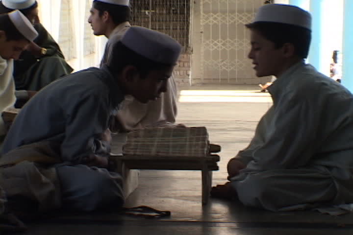 PESHAWAR, PAKISTAN - NOVEMBER 01, 2001: Two boys rock back and forth as they recite the Koran inside the Saudi-funded Darul Uloom Junadia Ghafooria.