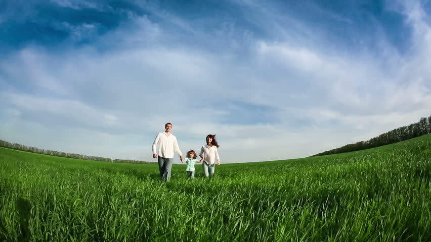 Happy family running in green field. Slow motion