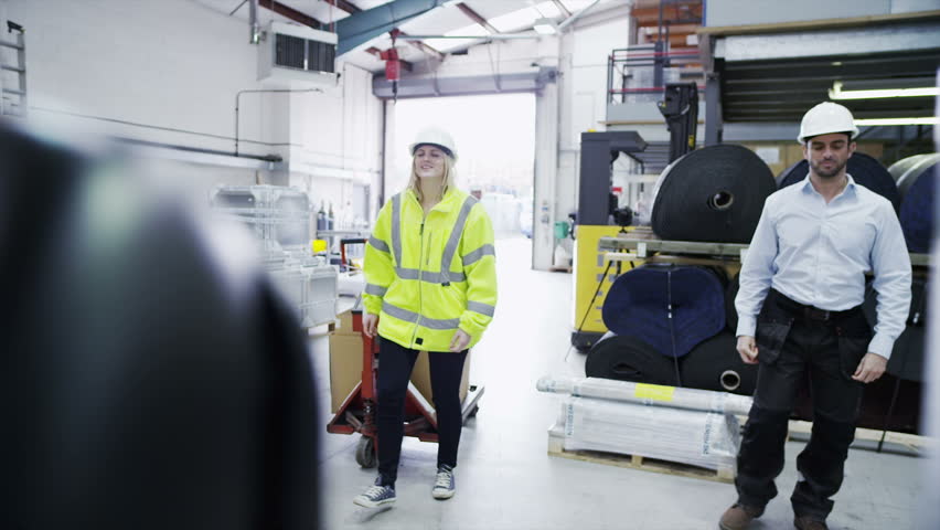 A male forklift truck driver arrives on shift in a factory or warehouse to take over from his female co-worker. In slow motion.