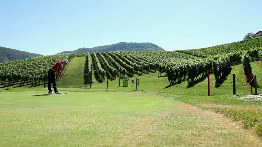 Shot of a woman golfer that hits a white golf ball with a golf club and the beautiful landscape in the background