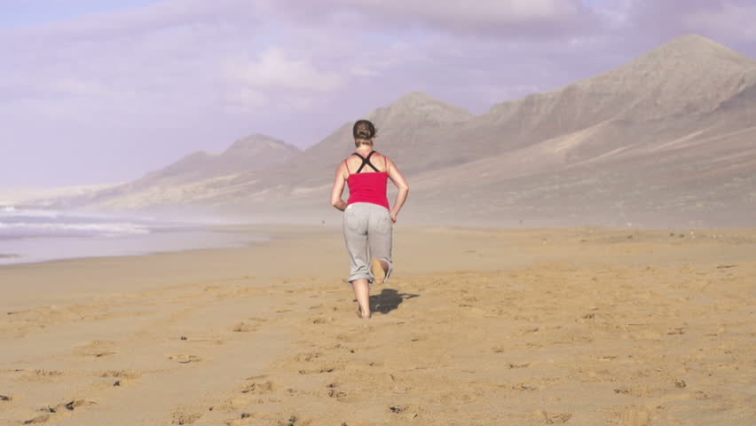 Young woman jogging on beautiful beach
